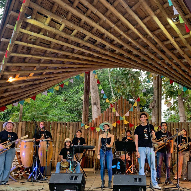 Presentación musical en vivo — Fundación Visión Raíces Banda musical juvenil toca en vivo bajo un escenario de bambú decorado con banderines, proyecto musical de la Fundación Visión Raíces
