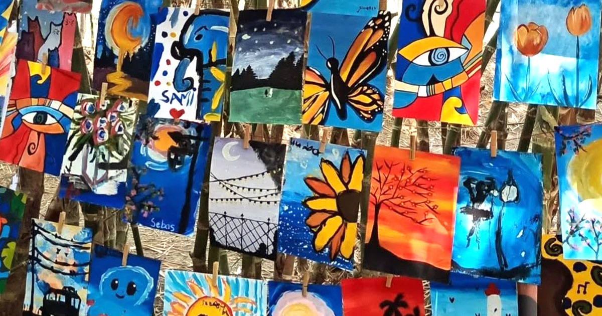 Decenas de pinturas de niños colgadas entre cañas de bambú, exhibición al aire libre del proyecto Finaroma Coloresvida de la Fundación Visión Raíces